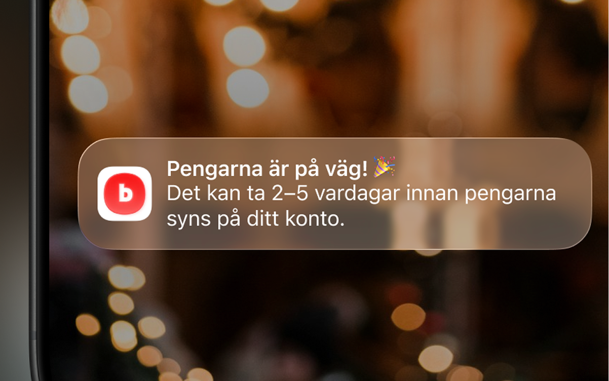 Närbild på en smartphone skärm som visar en notis från Blocket-appen där det står att pengar är på väg och kommer att synas på användarens konto om ca 2–5 arbetsdagar, över en varm, oskarp bakgrund med ljus.